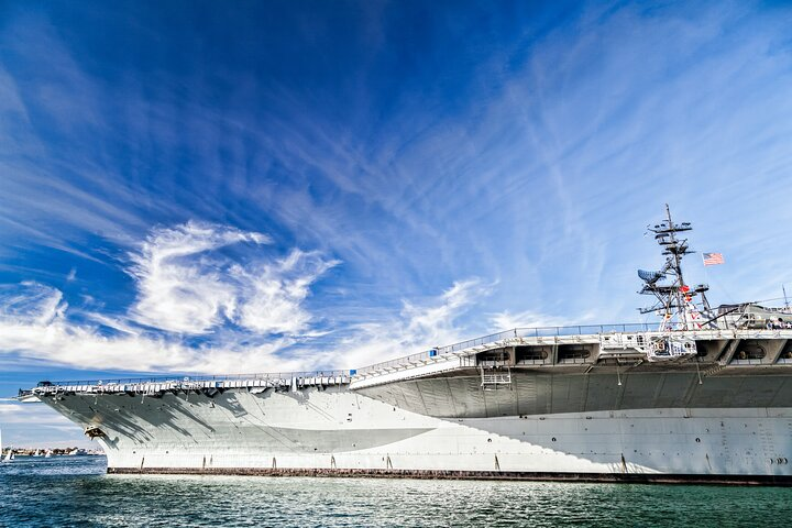 Experience the historic USS Midway against a stunning sky a massive former aircraft carrier inviting exploration of naval history while enjoying the serene beauty of San Diego Harbor.